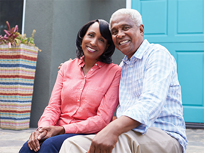 Black senior couple sitting on front steps of a house