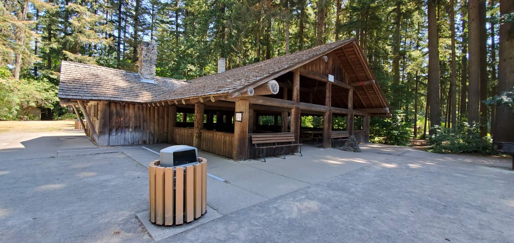 A wooden shelter at Lewisville Regional Park with benches, garbage cans and other amenities