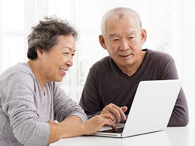 Mature Asian couple looking at a laptop computer screen