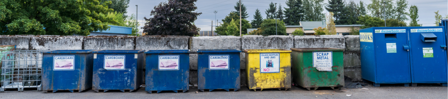 Self-service drop off recycling bins at the transfer station including cardboard, glass, scrap metal, and books. 