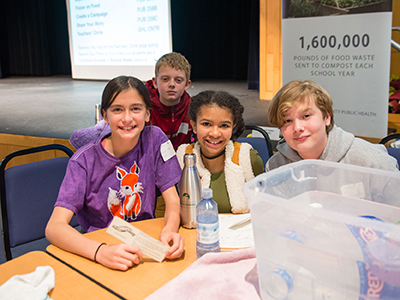 Two female and two male middle school students seated at a table attending Green Schools Summit