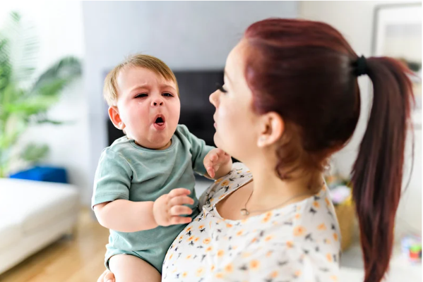 Image of woman holding a coughing child.