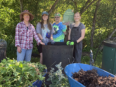 Four female volunteers in front of compost bins