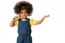 A little cute African-American girl brushing her teeth