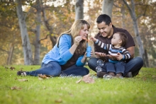 mom, dad, child blowing bubbles at the park